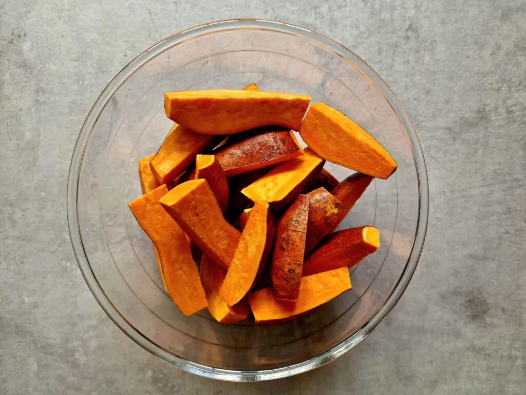 sliced raw sweet potatoes in a glass bowl