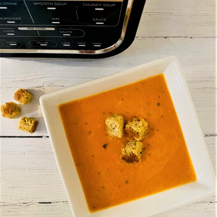 roasted red pepper tomato and mascarpone soup in a bowl with croutons next to Ninja Soup Maker
