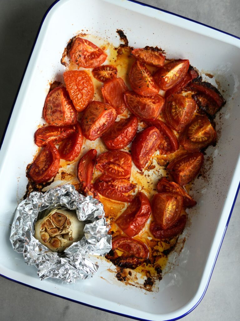 roasted tomatoes and garlic in a roasting tin