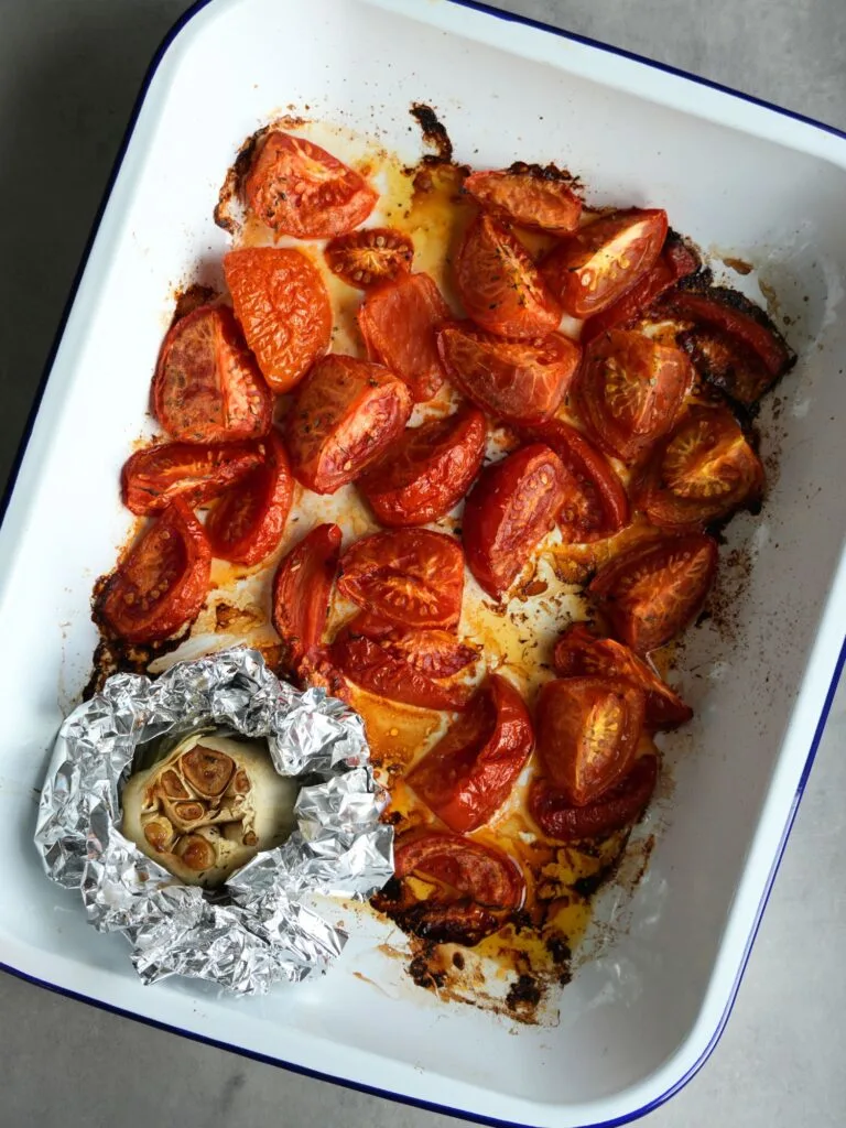 roasted tomatoes and garlic in a roasting tin