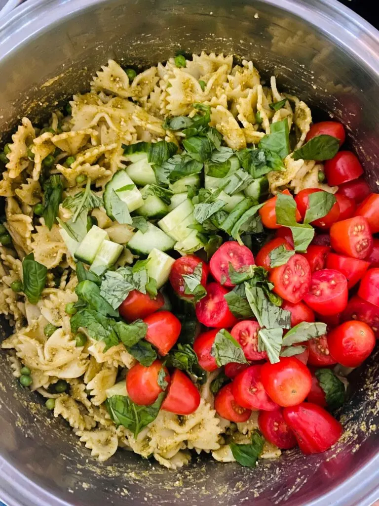 pesto pasta with chopped cucumbers, cherry tomatoes halved, fresh basil leaves, peas