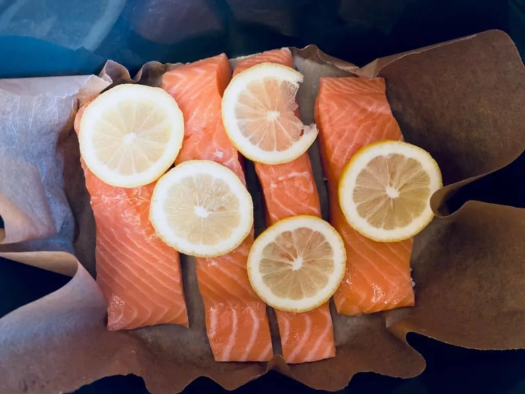 salmon on baking paper with lemons on top in a slow cooker