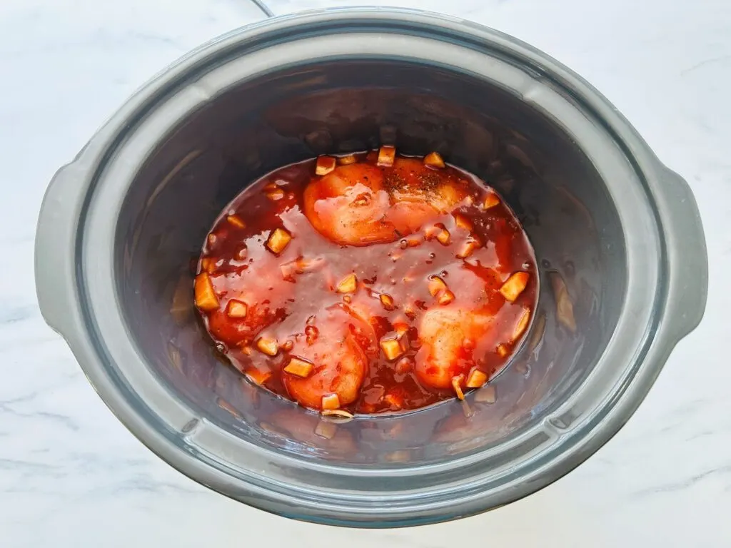 sauce poured over chicken in slow cooker to make pulled chicken