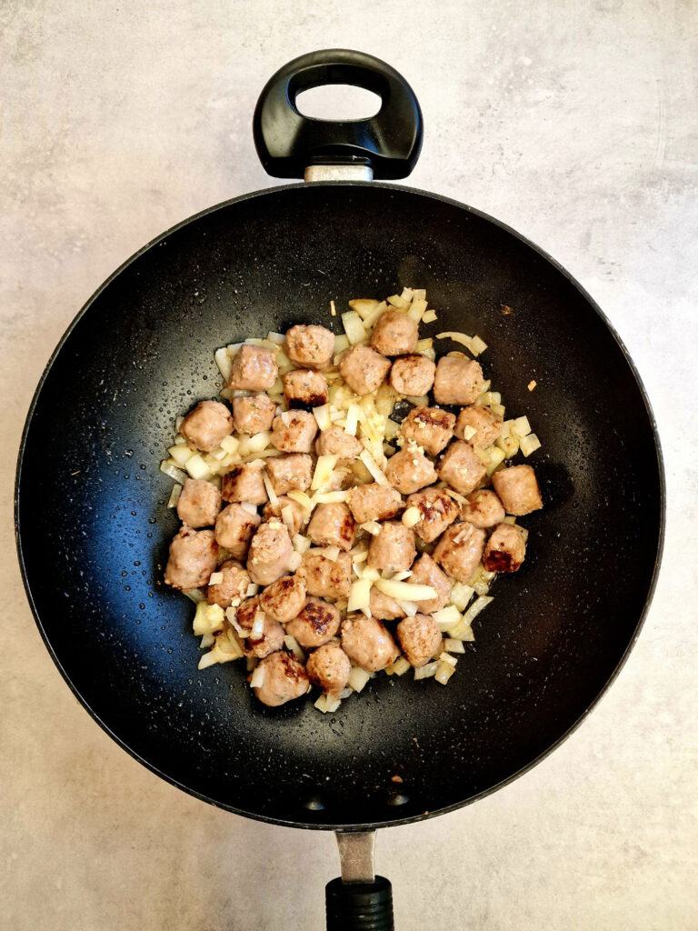 sausage chunks and onions softening in pan