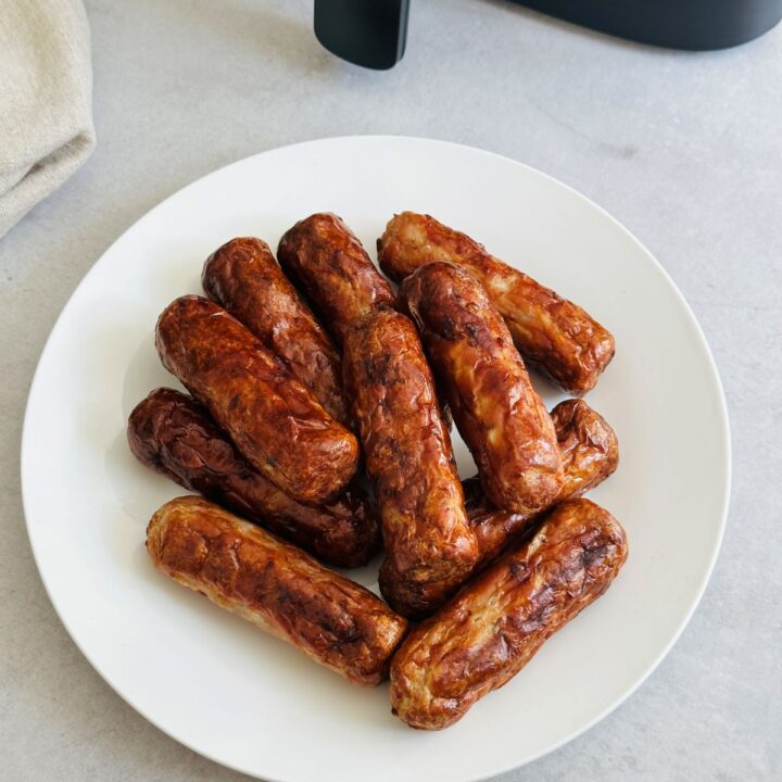 sausages on plate next to the air fryer
