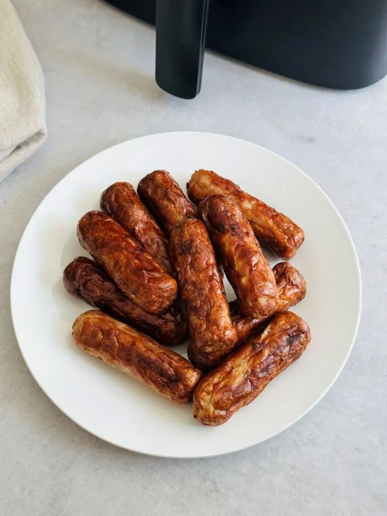 browned sausages on a plate next to an air fryer