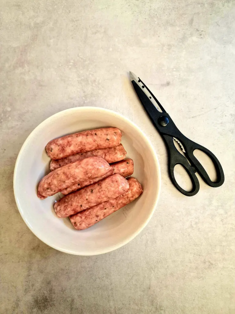 raw sausages with kitchen scissors