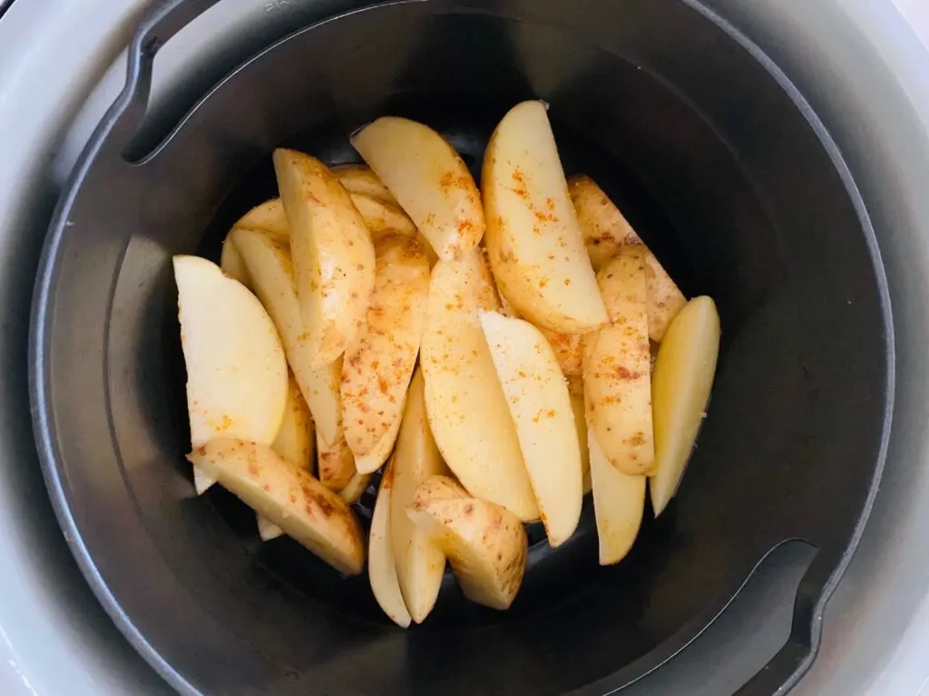 seasoned potato wedges sitting in the Ninja Foodi air fryer basket