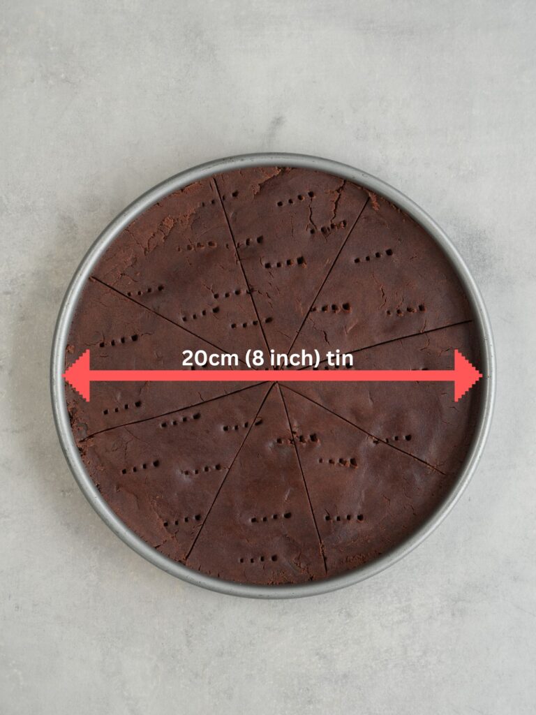 baking tin with chocolate shortbread dough inside with a red arrow showing the size of the tin (20cm / 8inch)