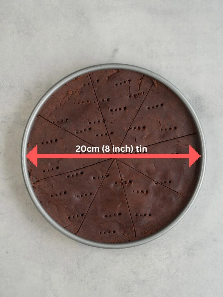 baking tin with chocolate shortbread dough inside with a red arrow showing the size of the tin (20cm / 8inch)