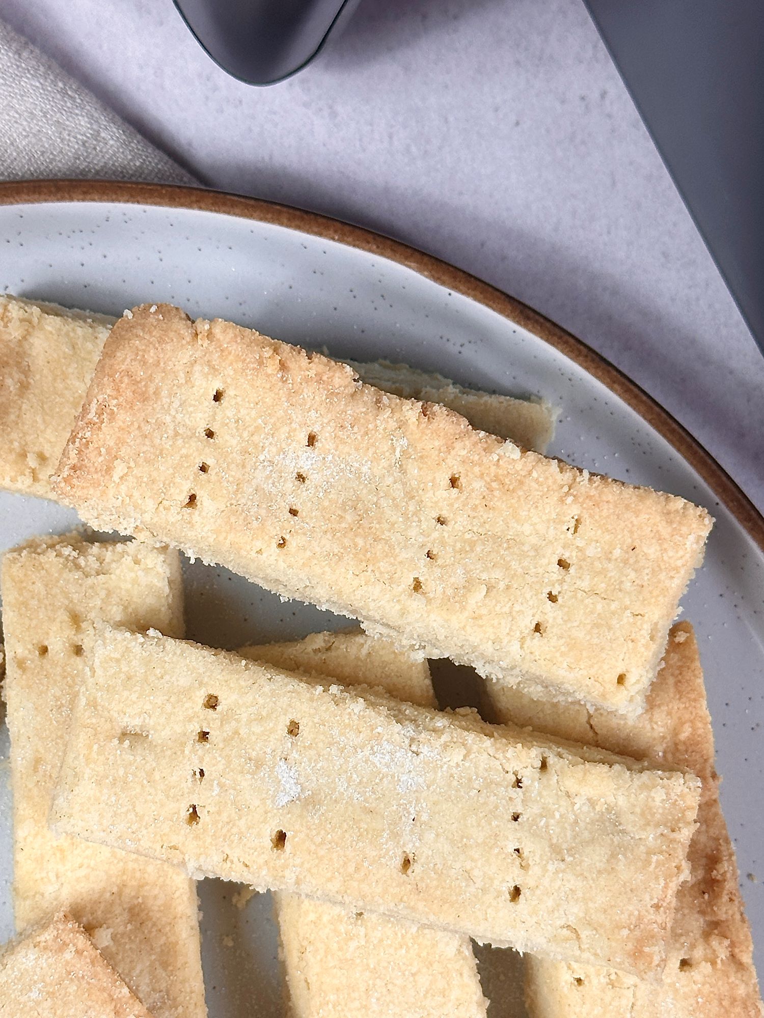 shortbread biscuits on a plate with sugar sprinkled over them next to an air fryer