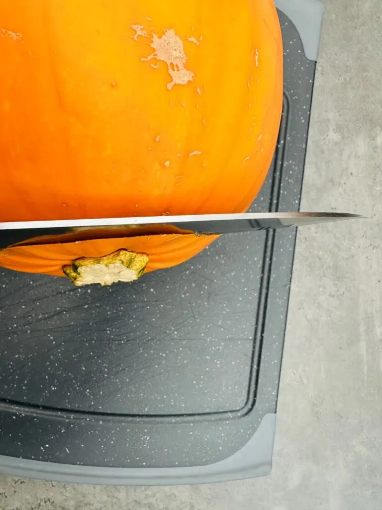 slicing top off pumpkin with a sharp knife