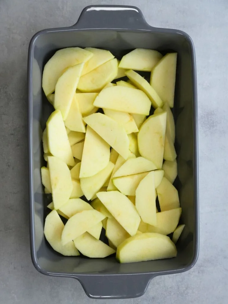 peeled and sliced bramley apples in a baking dish