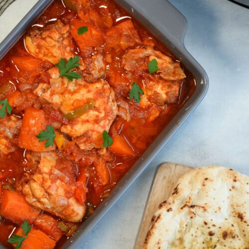 slow cooker chicken and sweet potato in a serving dish next to a naan bread