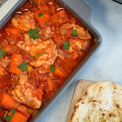 slow cooker chicken and sweet potato in a serving dish next to a naan bread