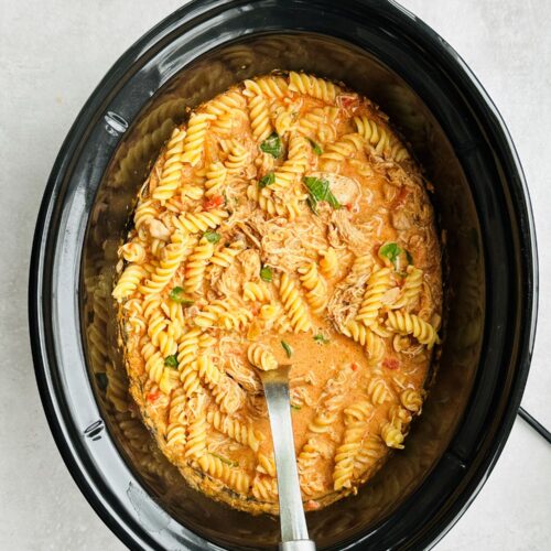 creamy tomato basil chicken recipe in a slow cooker with a serving spoon