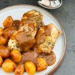 garlic chicken with potatoes and gravy poured over the top next to slow cooker