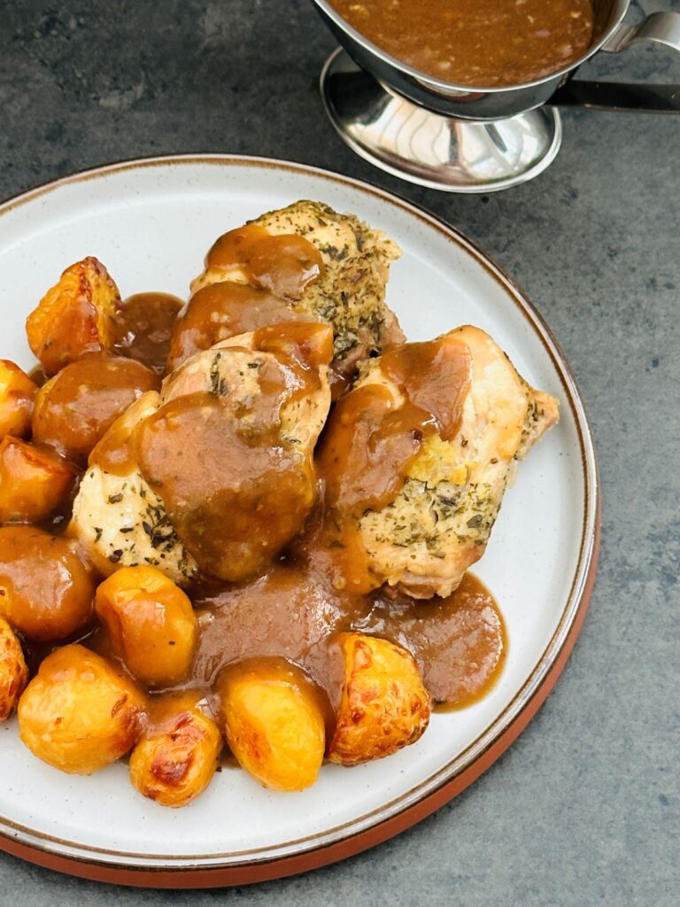 garlic chicken with potatoes and gravy poured over the top next to slow cooker
