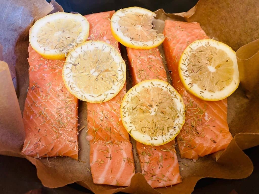 slow cooker salmon with sliced lemons and dried herbs on top