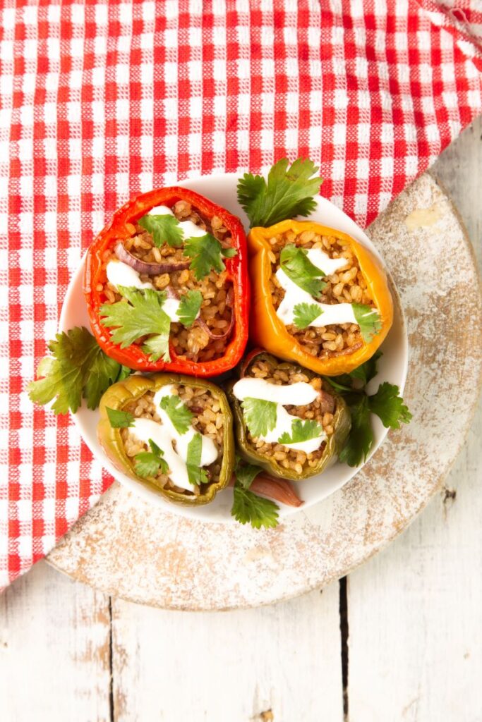 Stuffed peppers cooked in a slow cooker with fresh coriander and sour cream poured on top.