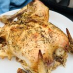 slow cooked whole chicken on plate next to slow cooker