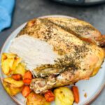 carved turkey crown with vegetables next to a slow cooker