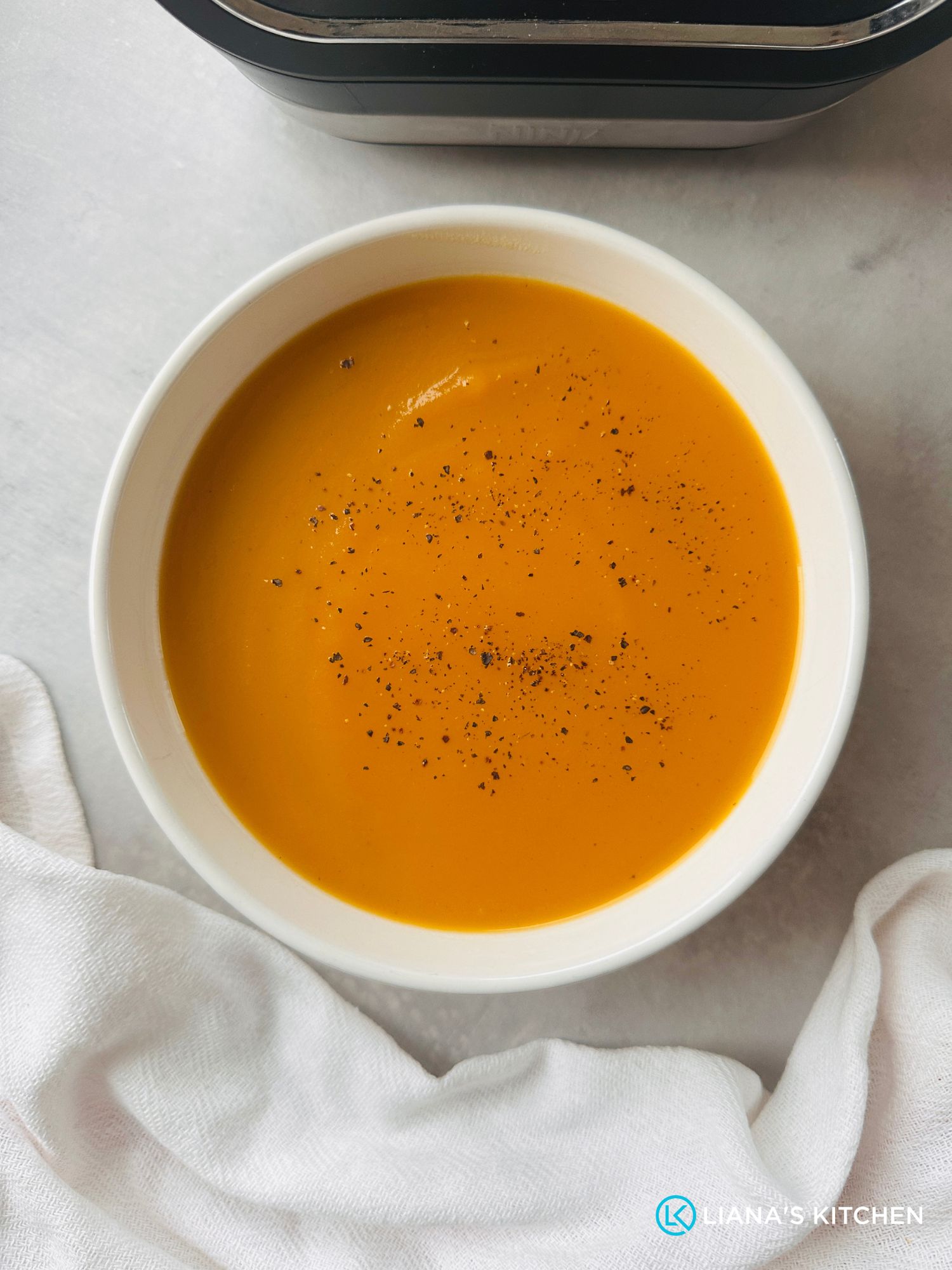 carrot and swede soup in a white bowl next to a ninja soup maker