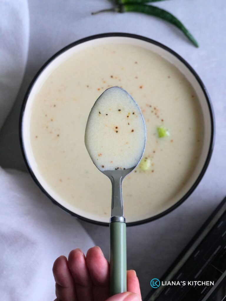 chicken soup on a spoon held above a bowl of soup