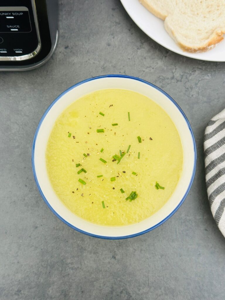 leek and potato soup in a bowl with chopped chives next to a Ninja soup maker
