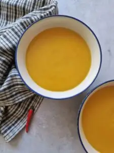 sweet potato and red chilli soup in two bowls with a red chilli next to them
