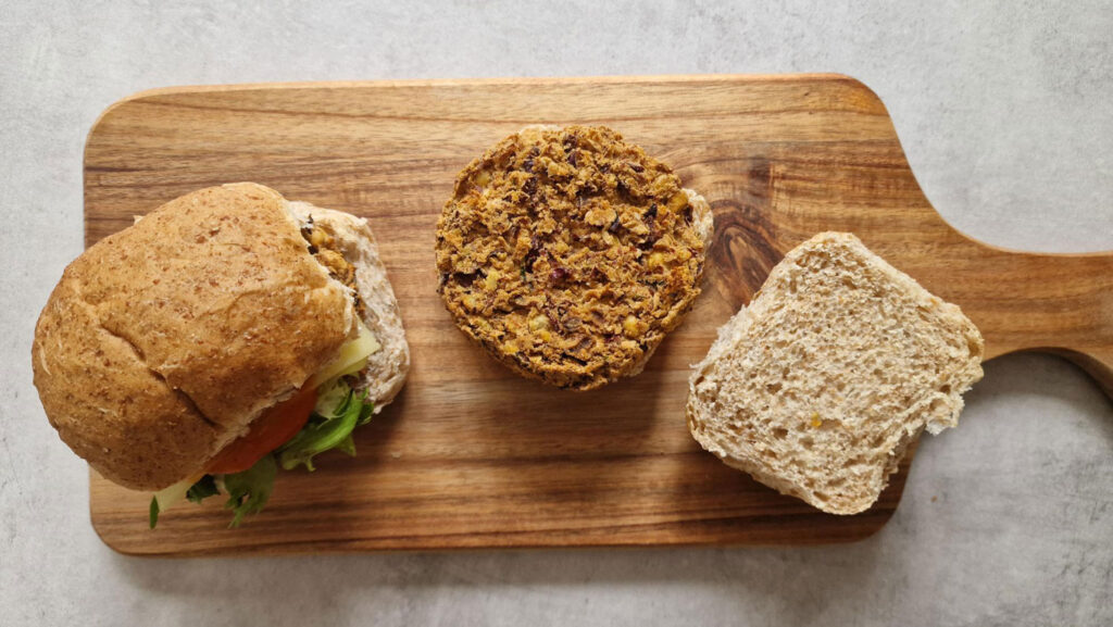 1 spicy bean burgers in baps on wooden board 