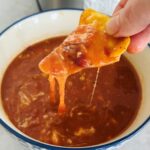 tortilla chip dipped into a spicy bean soup with melted cheese next to a Ninja soup maker