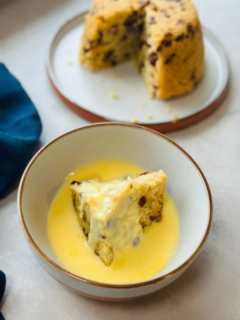 spotted dick sliced in a bowl with custard poured on top