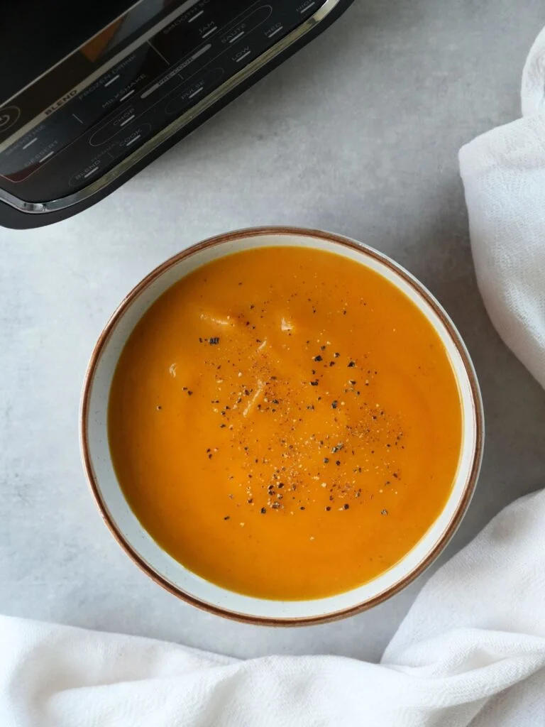 butternut squash and sweet potato soup in a bowl in front of a ninja soup maker