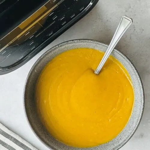 sweet potato and red lentil soup in a bowl next to a ninja soup maker