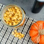 air fried pumpkin seeds in a jar next to an air fryer and a pumpkin