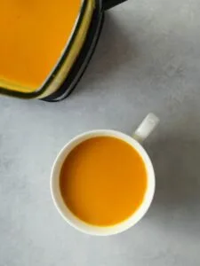 tikka butternut squash soup in a large white mug next to a Ninja soup maker