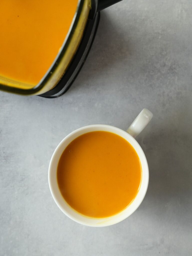 tikka butternut squash soup in a large white mug next to a Ninja soup maker