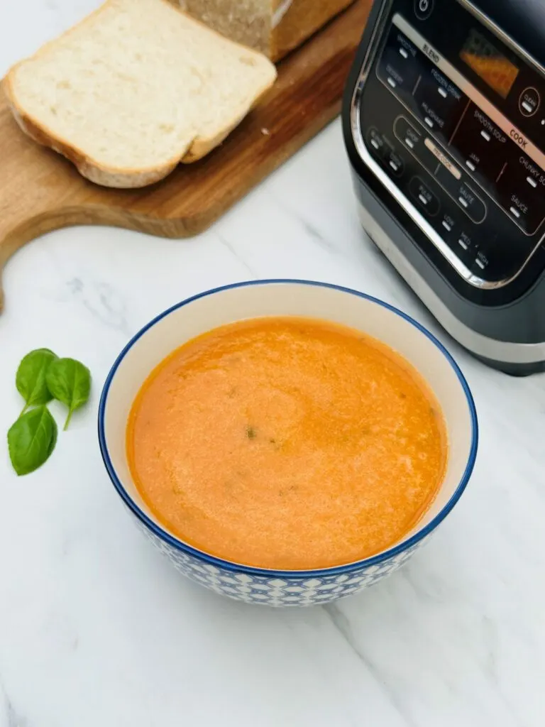 tomato soup in a bowl with basil leaves, fresh bread and ninja soup maker