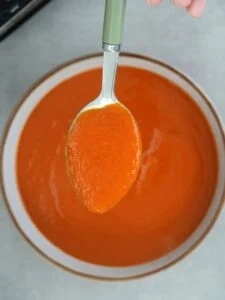spoon of tomato and butter bean soup above a bowl