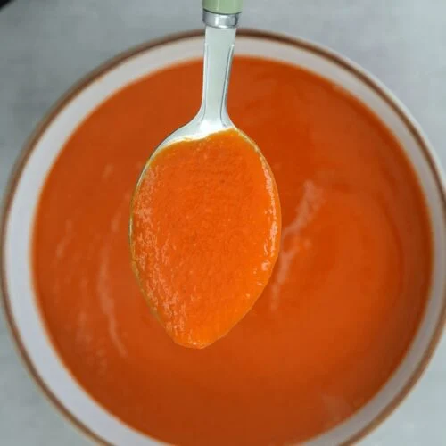spoon of tomato and butter bean soup above a bowl