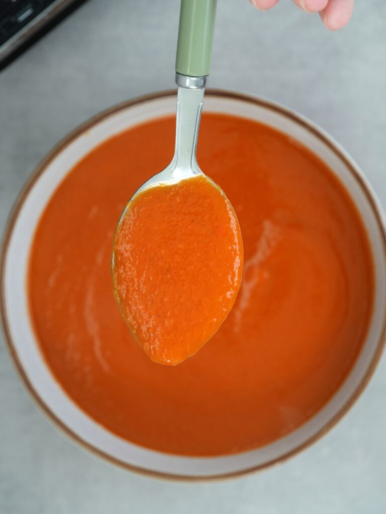 spoon of tomato and butter bean soup above a bowl