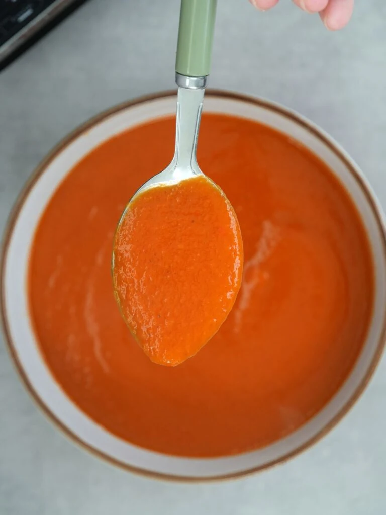 spoon of tomato and butter bean soup above a bowl