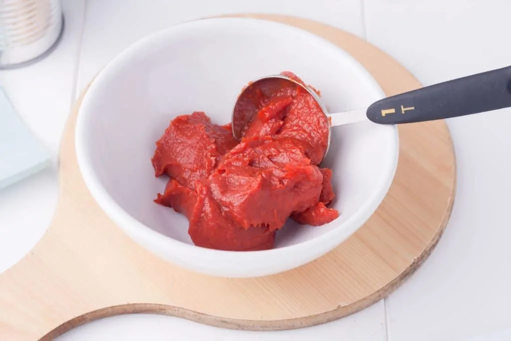 tomato puree in a white bowl on a wooden chopping board