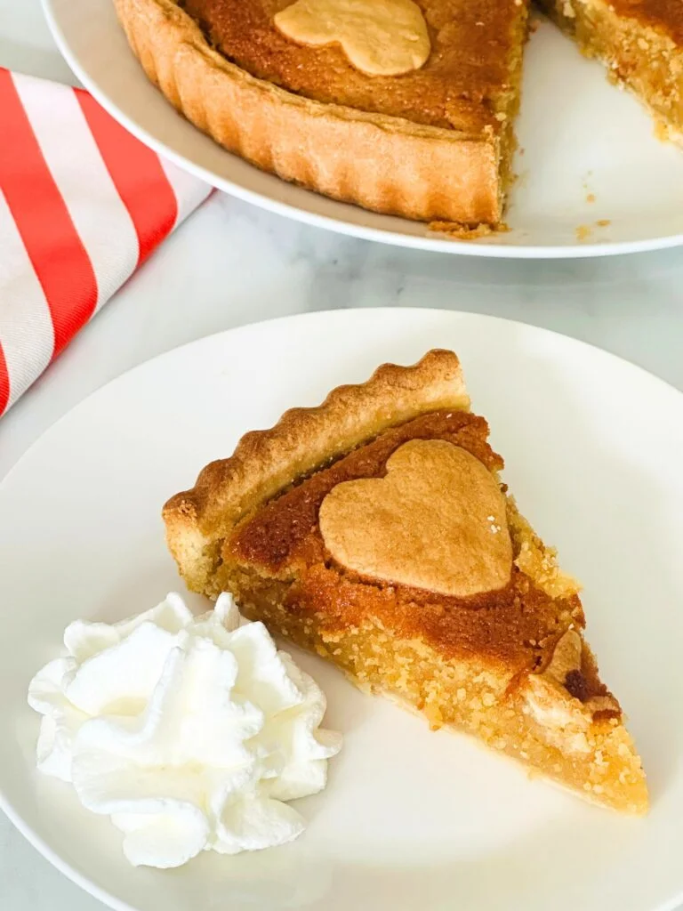 slice of treacle tart on a plate next to some squirty cream
