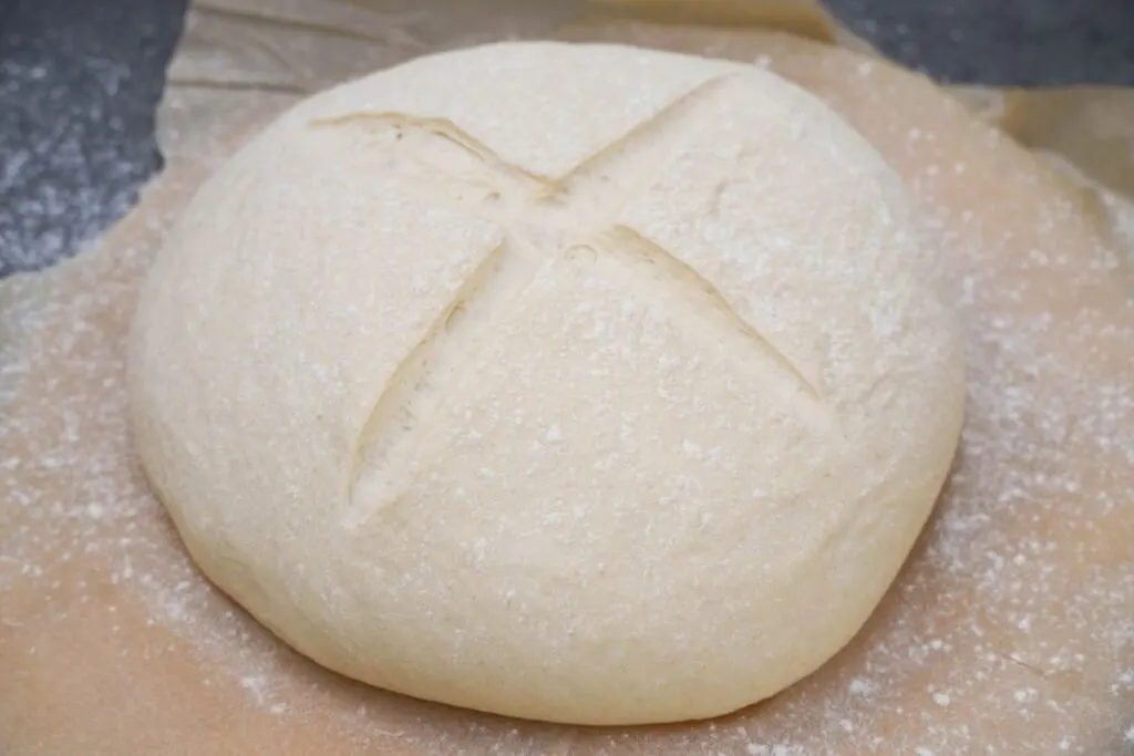 white bread dough scored with a cross