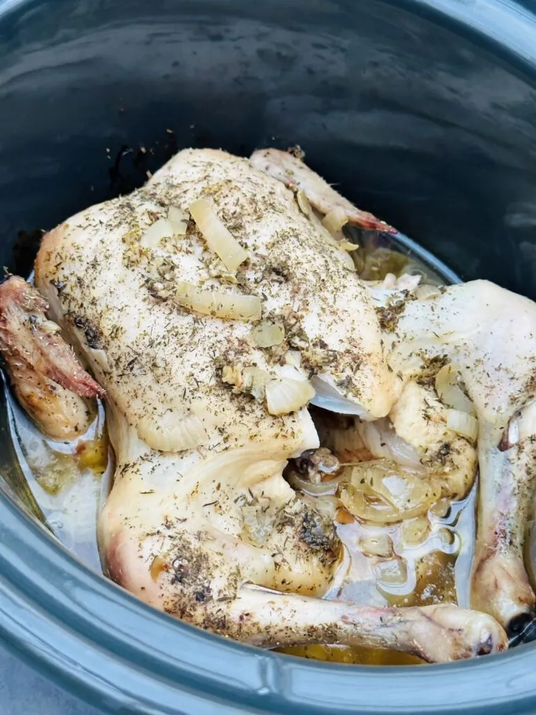 cooked whole chicken in liquid in slow cooker