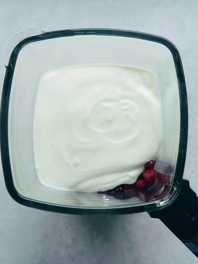 yoghurt in ninja blender on top of frozen berries